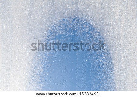 Water condensation on window and freezing snow on glass, transparent glass of window in winter and melting ice in contact with morning warm sunlight. Horizontal orientation, nobody.