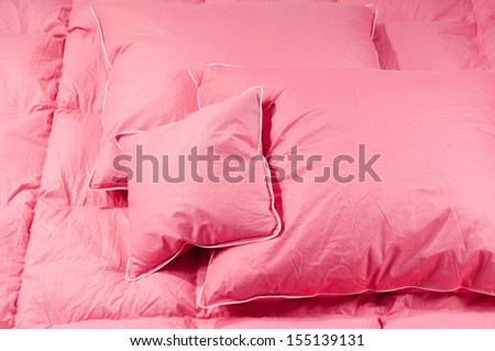 Cotton pink fluffy three pillows on duvet without cover, eiderdown filled with fluff or feathers. Horizontal orientation, nobody.