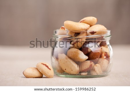 Brazil Nuts Lying In Glass Jar On Material