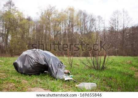 Garbage in black plastic bag dump in woods lying on fresh grass in early spring season, Clean Up the World gathering in Poland. Earth Day and nature dispose, horizontal orientation, nobody.