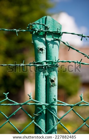 Green steel barbed wire fence, posts in vertical orientation, nobody, fencing detail in Poland.