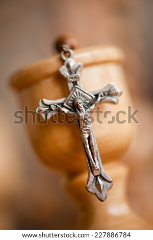 Cross on candlestick blurred rosary made of wood beads dangle on wooden cross, vertical orientation, nobody.