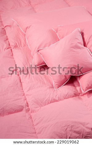 Cotton pink fluff duvet with pillows without cover, eiderdown filled with fluff or feathers. Vertical orientation, nobody.