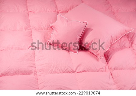 Cotton pink fluffy two pillows on big duvet without cover, eiderdown filled with fluff or feathers. Horizontal orientation, nobody.