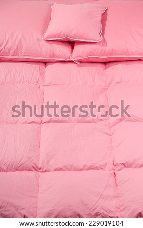 Cotton pink fluff duvet and pillows without cover, eiderdown filled with fluff or feathers. Vertical orientation, nobody.
