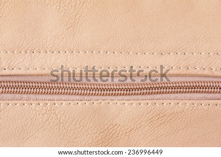 Beige zipper on leather cloth texture abstract, bright rough plain seam surface background in horizontal orientation, nobody.