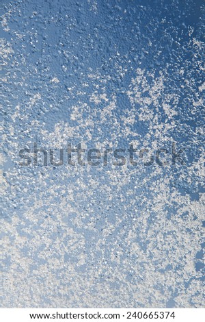 Snow and water condensation abstract on window glass, transparent glass in winter and ice with white snow in contact with morning warm sunlight, winter texture. Vertical orientation, nobody.