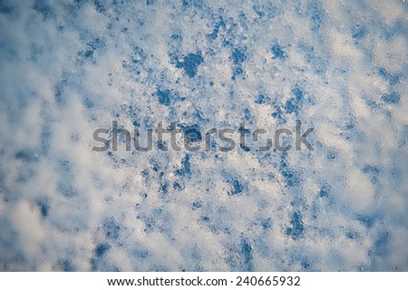 Melting snow and cold water, condensation on window glass, transparent glass in winter and ice with white snow in contact with morning warm sunlight. Horizontal, nobody, circle polarizer filter effect