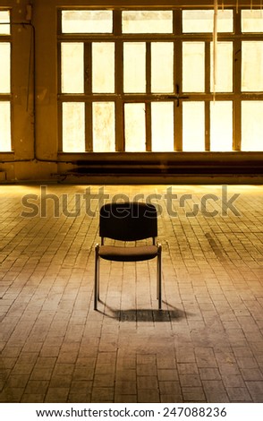 Lone chair empty hall full of yellow light coming through huge windows, furniture standing on floor in old abandoned magazine hall interior, vertical orientation, nobody.