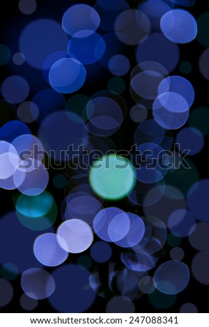 Blue bokeh circles blurry texture, sparkles defocused light abstract, blurred and out of focus lights on Christmas tree, glimmer dark mood light background in vertical orientation, nobody.