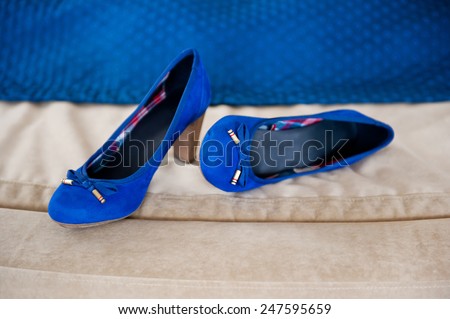 Female bridal two blue shoes on beige cloth in horizontal orientation, nobody. Pair of chamois leather elegance wedding shoes with bows.