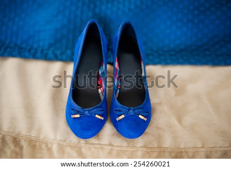 Female elegance bridal blue shoes on beige cloth in horizontal orientation, nobody. Pair of chamois leather wedding shoes with bows.