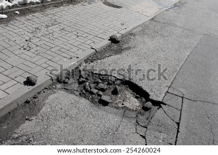 Bad chuckhole and rubbles in asphalt road damaged street in Warsaw, Poland, horizontal orientation, nobody.