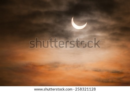 Partial solar eclipse and clouds morning sky in Poland, horizontal orientation, nobody. Cumulus formation partially block solar eclipse, warm colors of sun.