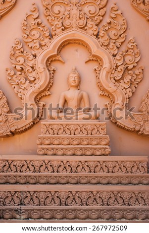 Buddha image with right hand on the knee and Thai traditional carving to decorate the wall of Buddhist church.
