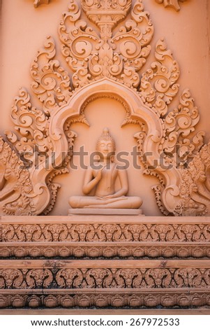 Buddha image with right hand in front of the chest and Thai traditional carving to decorate the wall of Buddhist church.