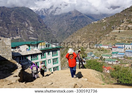 Everyday life in the settlement of Namche Bazar. Local porter goes up the road. Namche Bazar (3440 m), east Nepal, Himalayas. May 18, 2013
