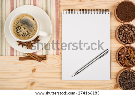 cup of coffee notebook and pen on the wooden table.