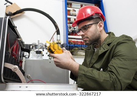 young adult electrician builder engineer worker in front of fuse switch board - focus on hand