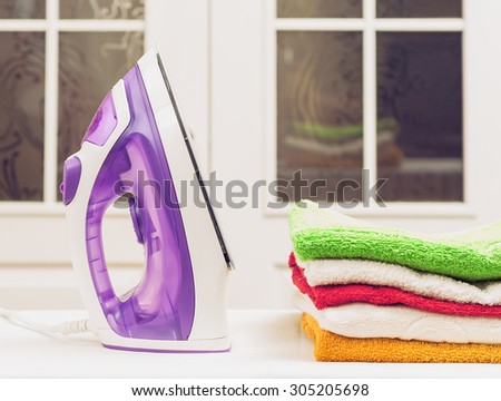 ironing, clothes, housework and objects concept - close up of iron and clothes on table at home.