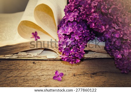 Blooming lilacs and old books on a wooden table.