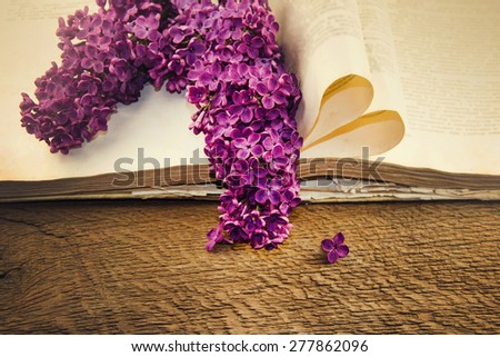 Blooming lilacs and old books on a wooden table.