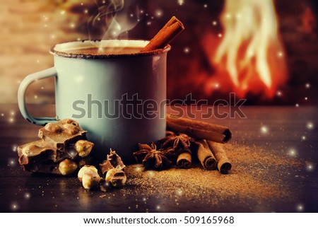 Vintage mug of hot chocolate with cinnamon sticks over dark background.