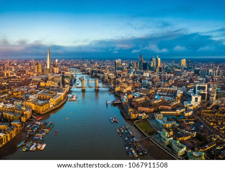 London, England - Panoramic aerial skyline view of London including Tower Bridge with red double-decker bus, Tower of London, skyscrapers of Bank District and Shard skyscraper at golden hour