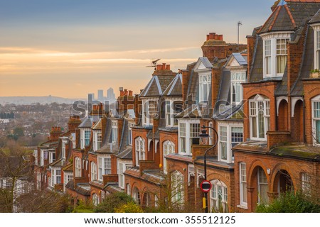 Typical British brick houses on a cloudy morning with sunrise and Canary Wharf at the background. Panoramic shot from Muswell Hill, London, UK