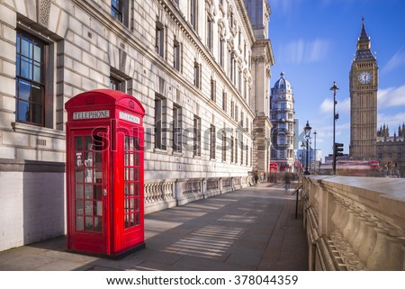 Traditional red british telephone box with Big Ben and Double Decker bus at the background on a sunny afternoon with blue sky and clouds - London, UK