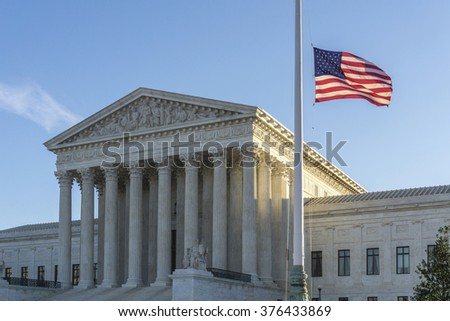 WASHINGTON, DC, USA - FEBRUARY 14, 2016: Flags fly at half-staff at the United States Supreme Court as the sun rises on the first day after Justice Antonin Scalia\'s death was announced.