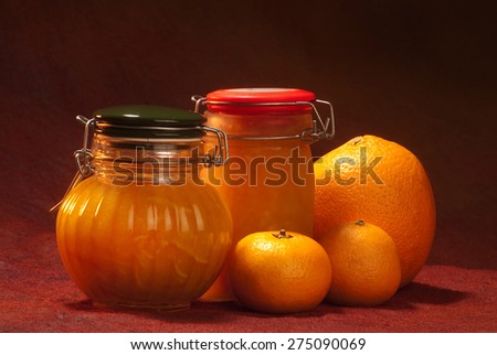 orange/clementine marmalade jars with fresh fruit placed on the side (orange and clementine), placed on a dark reddish brown