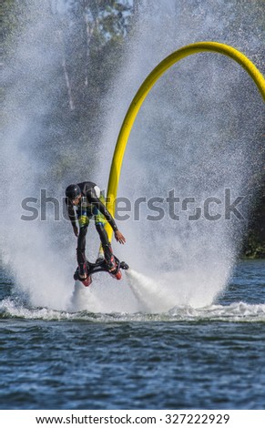 A man on a fly-board is rising over the water of the St-Lawrence river, push by the jet of the fly-board in verdun quebec, photo taken on 24th of september 2015