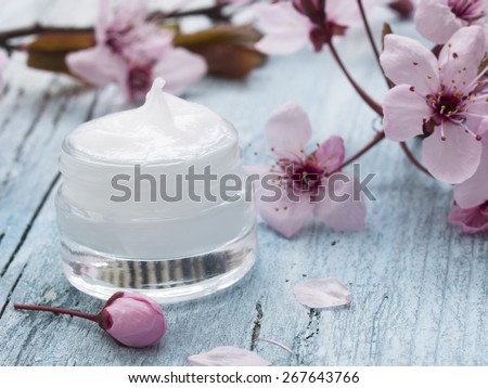 natural facial cream with beauty  cherry blossoms on wooden background
