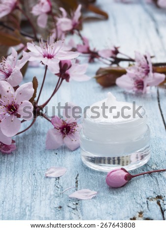natural facial cream with beauty  cherry blossoms on wooden background
