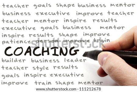 A hand writing the word Coaching in bold letters surrounded by great terms such as improve, leader, shape, teacher, mentor and more.