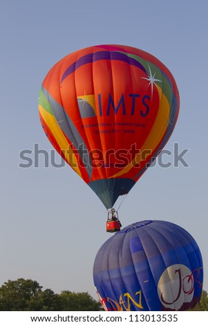 SEYMOUR, WI - AUGUST 3: An orange IMTS hot air balloon starts to ascend next to the Jordan balloon at the Balloon Rally at the Annual Hamburger Festival on August 3, 2012 in Seymour, Wisconsin.