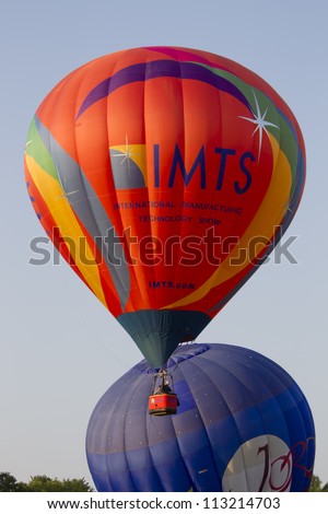 SEYMOUR, WI - AUGUST 3: An orange IMTS hot air balloon starts to ascend in the sky next to the Jordan balloon at Balloon Rally at the Annual Hamburger Festival on August 3, 2012 in Seymour, Wisconsin.