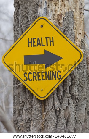 A yellow sign on a tree showing which way for Health Screening making a great employer health insurance screening concept.