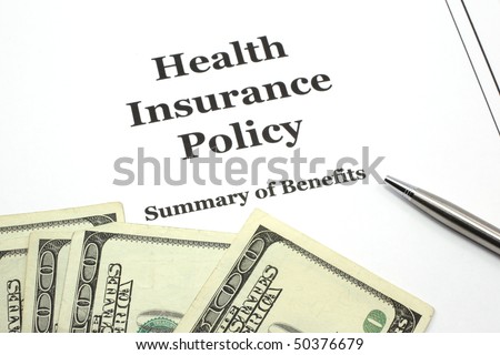 A health insurance policy with a pen ready for signing surround by cash in hundred dollar bills.