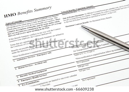 An HMO benefits summary with a pen outlining the health insurance coverage plan.