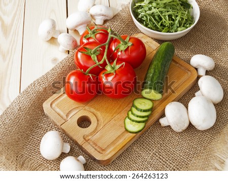 cucumbers, tomatoes, mushrooms and arugula on a wooden Board