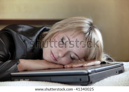 The young beautiful girl in a business suit has got tired and sleeps on the laptop