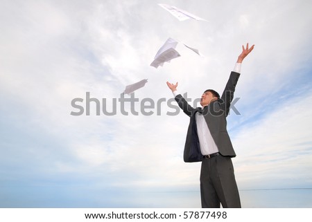 young guy in a business suit with joy throwing papers in the sky