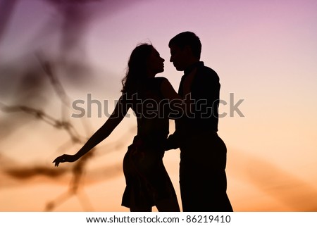 Beautiful couple in love in kontrazhur at sunset. Silhouette guys and girls at sunset. They dance.