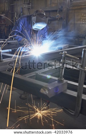 man with mask welding at steel construction at workshop