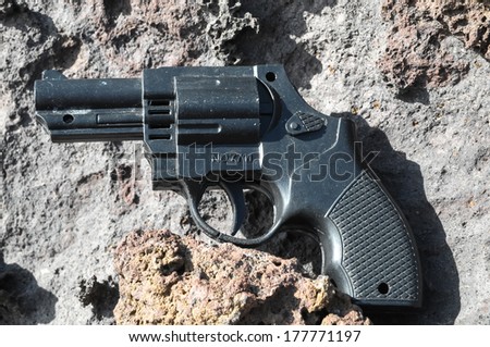 Plastic Revolver Gun Toy on the Volcanic Rocks