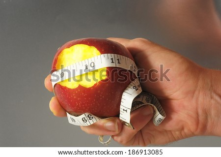 Bitten Diet Apple and Meter the Hand on a Colored Background