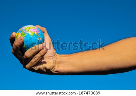 Vintage Old Globe Earth and Human Hand over a Blue Sky