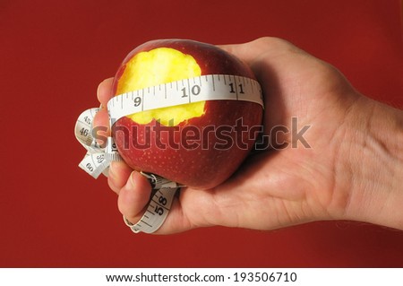 Bitten Diet Apple and Meter on the Hand on a Colored Background